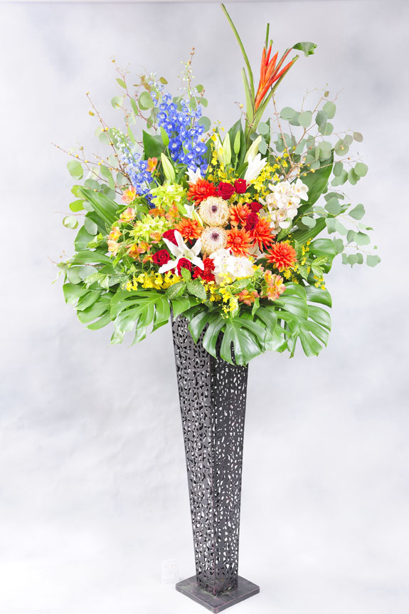 <p>様々な色の稀少花材と黒ブリキスタンドで仕立てたスタンド花です。</p>