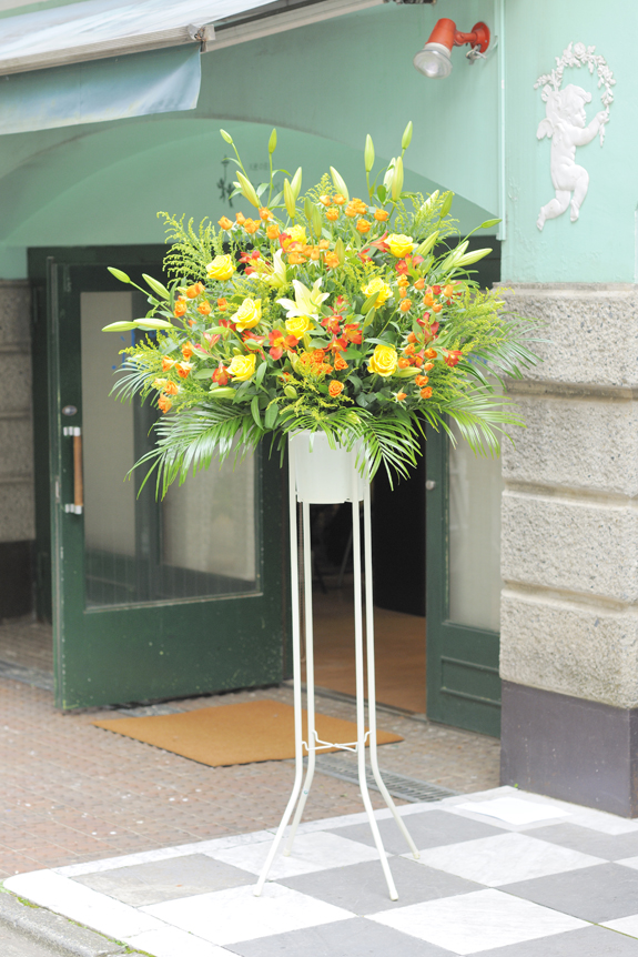 温かみ溢れる黄色とオレンジを中心とした暖色系2色仕立てのスタンド花です。