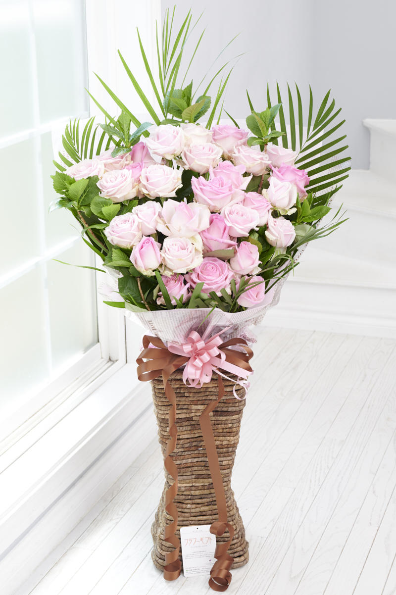 お洒落なバナナリーフのスクエア型の花器に入ったお洒落な高級薔薇スタンドフラワー商品です。