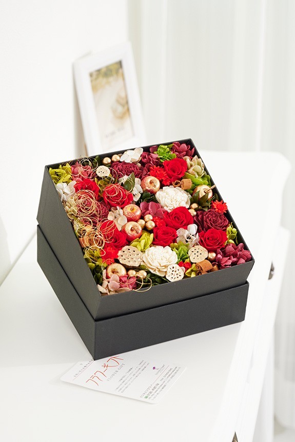 蓋を開けると、華やかな赤・グリーン・白系のお花が顔を出す、クリスマスをイメージしたプリザーブドフラワー作品です。