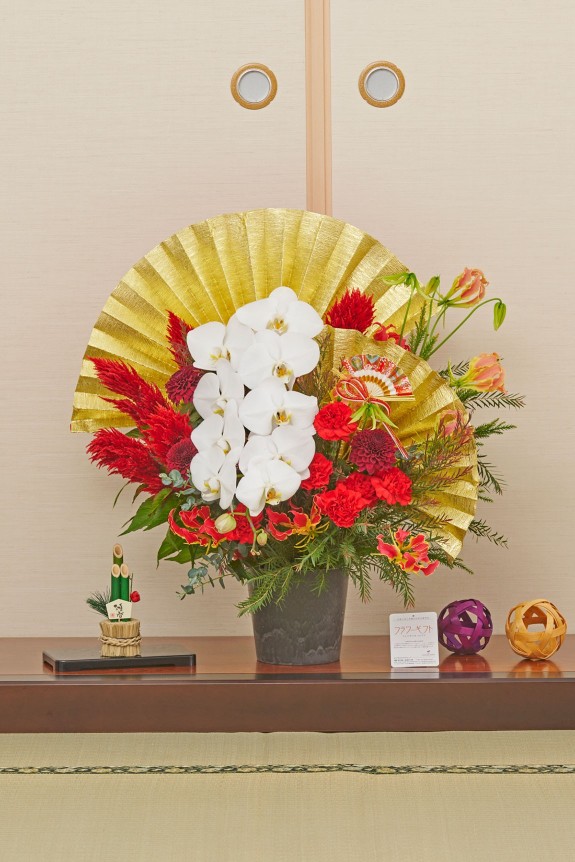 大きな黄金の扇飾りが目に留まる、新春飾りに相応しい豪華な赤系のアレンジメントフラワーです。