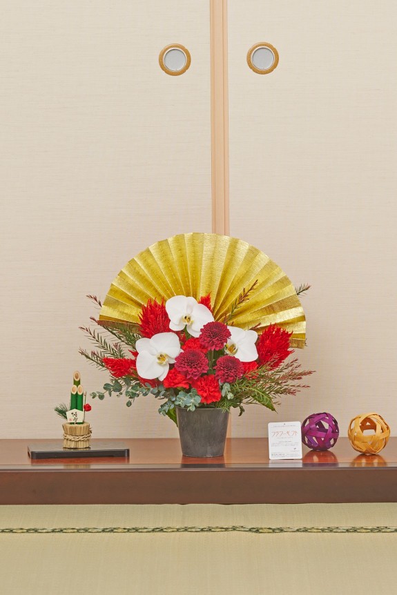 大きな黄金の扇飾りが目に留まる、新春飾りに相応しい豪華な赤系のアレンジメントフラワーです。