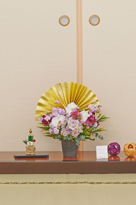 大きな黄金の扇飾りが目に留まる、新春飾りに相応しい豪華な紫系のアレンジメントフラワーです。