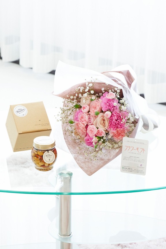 母の日の定番カーネーション＆皇室献上、農林水産大臣賞の受賞実績のあるバラ農園のバラをミックスさせた花束・ブーケに「いつもありがとう」の3D立体ピックを挿したお花と、ハンガリー大使館認証を受けたハンガリー産アカシアはちみつにこだわりのミックスナッツを漬け込んだナッツの蜂蜜漬けをセットにしたフラワーギフト用の商品です。