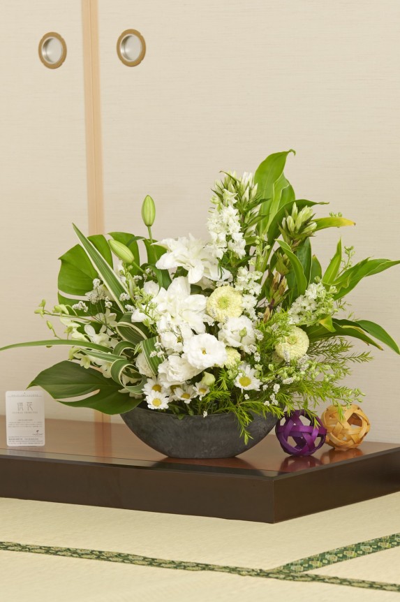 お洒落でスマートな花器に、白＆グリーンの花材で仕立てたデザイナーズ供花アレンジメント商品です。