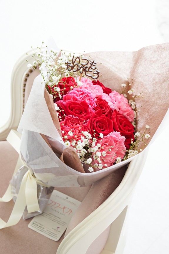 母の日の定番カーネーション＆皇室献上、農林水産大臣賞の受賞実績のあるバラ農園のバラをミックスさせた花束・ブーケに、「いつもありがとう」の3D立体ピックを挿したフラワーギフト用の商品です。