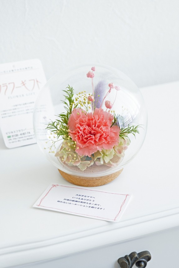 ガラスドームの中に、母の日の定番でもあるカーネーションを中心に仕立てたデザイナーズプリザーブドフラワー商品です。