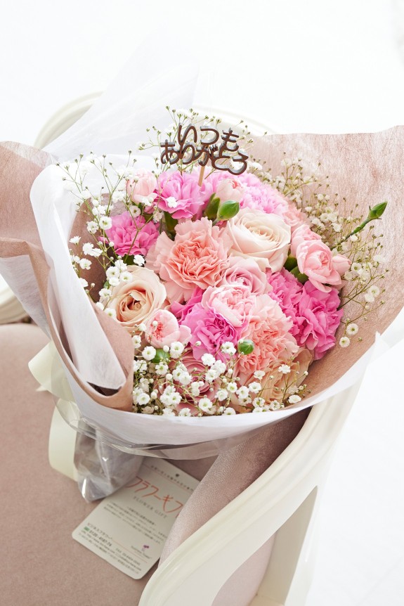 母の日の定番カーネーション＆皇室献上、農林水産大臣賞の受賞実績のあるバラ農園のバラをミックスさせた花束・ブーケに、「いつもありがとう」の3D立体ピックを挿したフラワーギフト用の商品です。