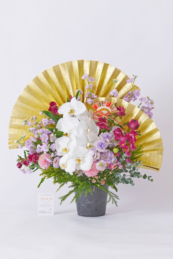 大きな黄金の扇飾りと純白の胡蝶蘭が目に留まる、大切なお祝いに相応しい豪華な紫色系のアレンジメントフラワーです。