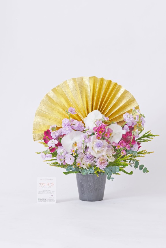 大きな黄金の扇飾りと純白の胡蝶蘭が目に留まる、大切なお祝いに相応しい豪華な紫色系のアレンジメントフラワーです。