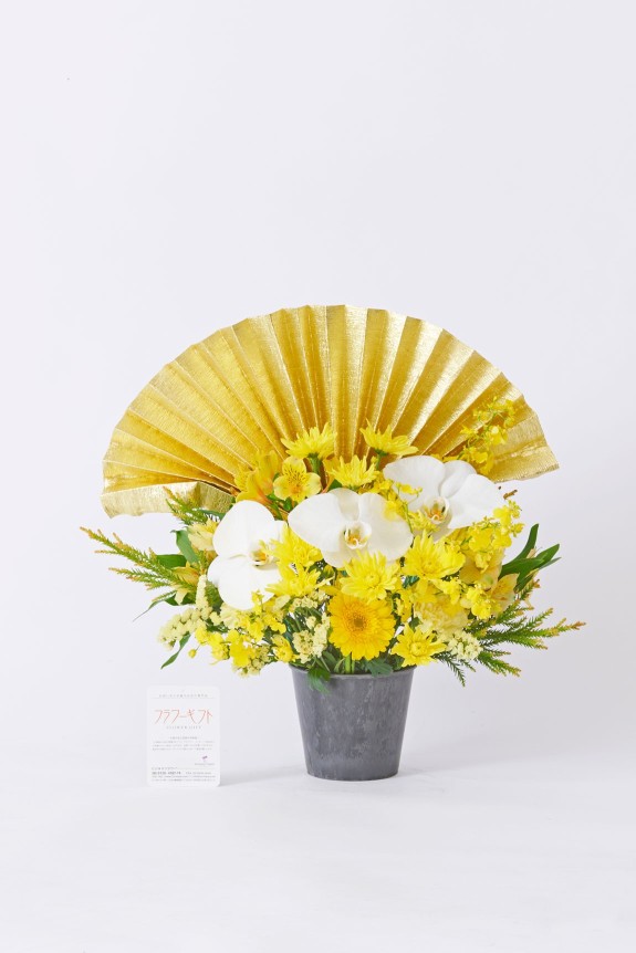 大きな黄金の扇飾りと純白の胡蝶蘭が目に留まる、大切なお祝いに相応しい豪華な黄色系のアレンジメントフラワーです。