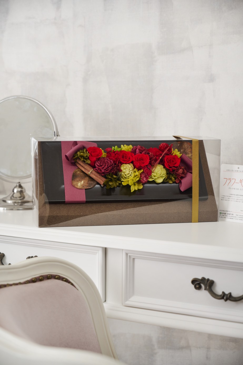 グレーのフレームに赤やグリーンの色合いでまとめられたスタンドタイプのプリザーブドフラワー。